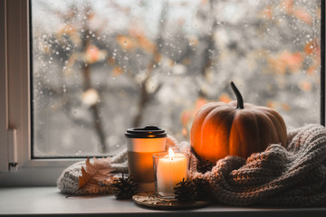 Cup of coffee, pumpkin, dried autumn leaves on window. Autumn composition.