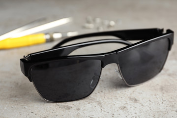 Stylish sunglasses and fixing tools on grey table