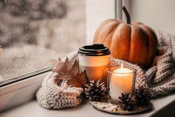 Cup of coffee, pumpkin, dried autumn leaves on window. Autumn composition.
