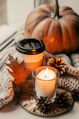 Fototapeta na wymiar Cup of coffee, pumpkin, dried autumn leaves on window. Autumn composition.