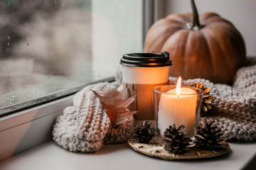 Cup of coffee, pumpkin, dried autumn leaves on window. Autumn composition.