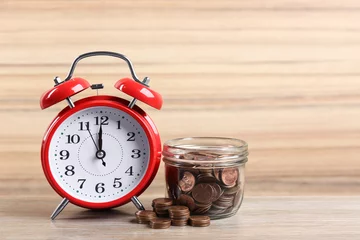 Fotobehang Red alarm clock, glass jar and coins on table against wooden background. Money savings © New Africa