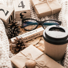 Winter composition. Cup with coffee, glasses, cones on a sweater background.