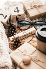 Winter composition. Cup with coffee, glasses, cones on a sweater background.