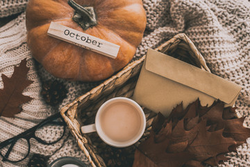 Cup of cocoa, nuts, pumpkin, glasses, dried autumn leaves on sweater background. Autumn composition.