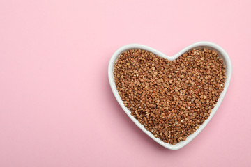 Buckwheat grains on pink background, top view. Space for text