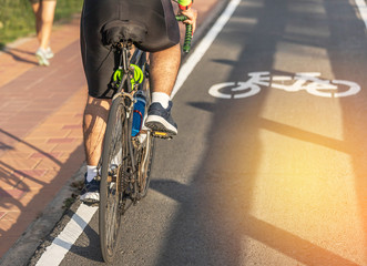 Fototapeta premium Rowerzysta jedzie na rowerze do ćwiczeń w parku drogowym z białym pasem rowerowym znak w koncepcji zdrowego stylu życia po południu
