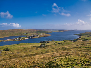 Fototapeta na wymiar A view of Weisdale Voe on the west of Mainland, Shetland, Scotland, UK, taken on a sunny day with a blue sky and light clouds the houses at Kalliness and the Loch of Hellister appear on the left.