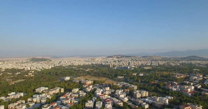 Athens Greece at sunrise with massive city and the acropolis in the distance at sunrise. Realtime aerial drone shot of a huge sprawl of houses apartments and buildings.