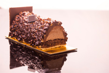 Christmas chocolate log cake covered with chocolate glaze and hazelnut