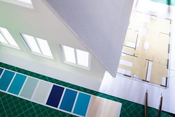 Architectural design. Drawing lies on the table next to the model of the house. Designer desktop. Work on the facade of the house. Development design concept creation. Work in an architectural bureau