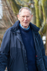 Handsome elderly gentleman wearing a blue coat in a rural setting
