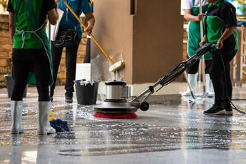The workers cleaning floor exterior walkway using polishing machine and chemical or acid