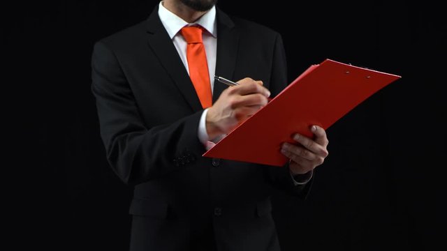 Man fills papers in red folder with pen, then looks through them. Concept of planning, business. Mockup ready for your text or product.