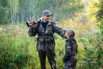Father teaching his son about gun safety and proper use on hunting in nature.