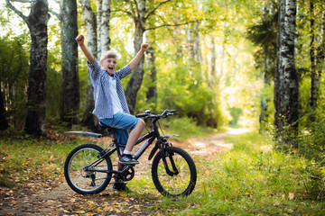 Naklejka premium Boy riding a bike outdoors in the grass on a sunny day with hands raised