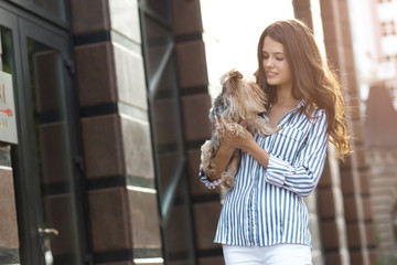 Girl walks with a dog in the city street.