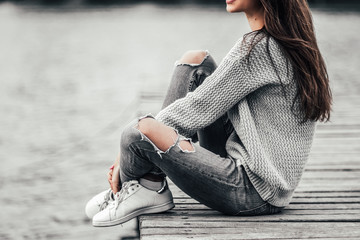 Beautiful dreaming woman sitting on pier by the lake.