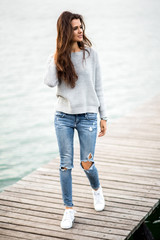 Beautiful dreaming woman walking on pier by the lake.