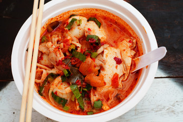 Spicy noodle with fish meat in hot soup on wood table