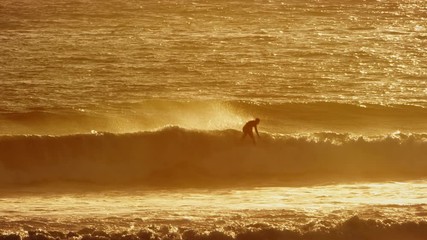 Surfer does an air out of a wave at sunset - Powered by Adobe