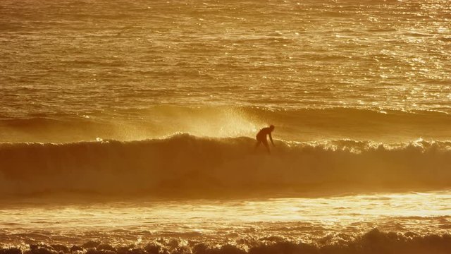 Surfer does an air out of a wave at sunset