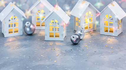 winter silver background with decorative lights in form of wooden houses and christmas tree balls