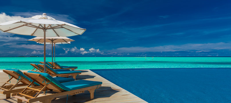 Deck chairs with umbrellas at Maldives resort with infinity pool and beach