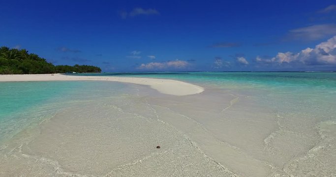 Tide is rising and shallow water start to sink white sandy dunes of long tail beach in Cook islands