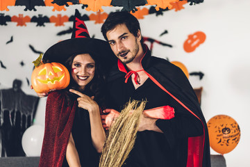 Couple having fun holding pumpkins and wearing dressed carnival halloween costumes and makeup...