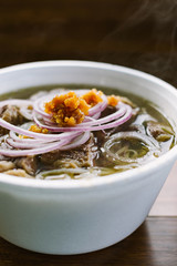 Styrofoam bowl of fresh steaming hot traditional beef and rice noodle Vietnamese pho soup with...