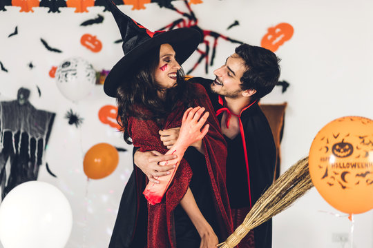 Couple having fun holding pumpkins and wearing dressed carnival halloween costumes and makeup posing with bats and balloons on background at the halloween party.Halloween holiday celebration concept - Powered by Adobe