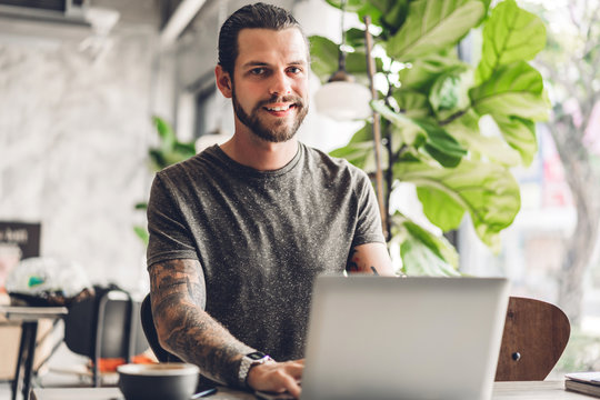 Handsome Bearded Hipster Man Use And Looking At Laptop Computer With Coffee At Table In Cafe.Communication And Technology Concept