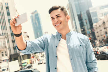Outdoors Leisure. Stylish guy standing on the street taking selfie smiling cheerful