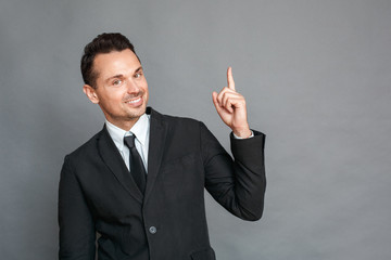 Businessman studio standing isolated on grey pointing up creative idea smiling joyful
