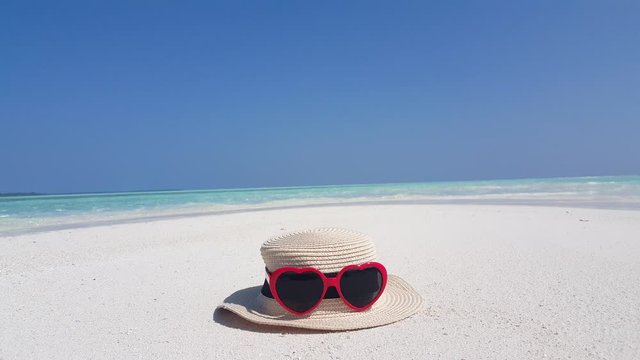 Concept design with sunglasses and straw hat over white sand on Caribbean seascape background