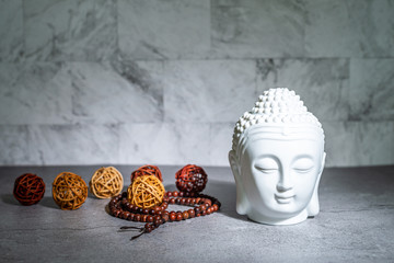 Home decoration ornament. White buddha head face, rattan cane balls. Marble texture wallpaper...