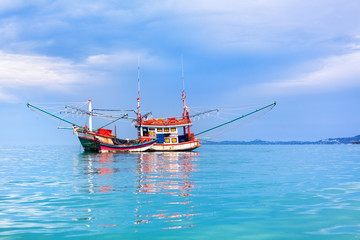 Fisherman boat on blue sea, sky, clouds landscape background close up, beautiful seascape with red wooden fishing vessel on turquoise water, traditional asian orange fishing trawler ship in Thailand