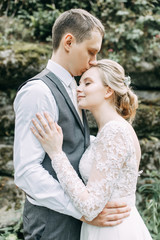 Fototapeta premium Modern ceremony in European style. Beautiful wedding couple in atmospheric forest with rocks.
