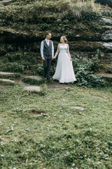 Modern ceremony in European style. Beautiful wedding couple in atmospheric forest with rocks.