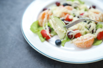 fork picking green apple from fruit salad 