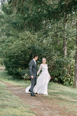 Fototapeta premium Modern ceremony in European style. Beautiful wedding couple in atmospheric forest with rocks.