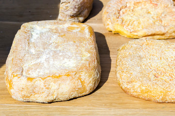 mix of various varieties of hard cheese on a wooden board.