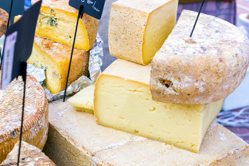 mix of various varieties of hard cheese on a wooden board. View from above.