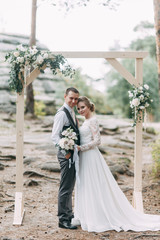 Fototapeta premium Beautiful couple at sunset in the Park. Wedding ceremony with arch in the forest.