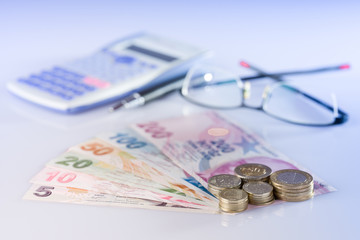 Turkish banknotes and Turkish coins. image of calculator, glasses and pen on work desk 5,10,20,50,100,200 Turkish Lira front side and 5, 10, 25, 50 kurus .close up