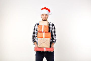 Holidays and presents concept - Funny man in Christmas Santa hat holding many gift boxes on white background