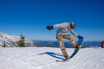 Ski resort. Snowboarder jumping on a snowboard in the mountain. Long jump on a snowboard.