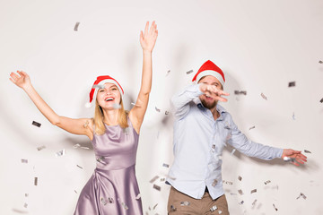 Obraz premium New year, christmas and party concept - Cheerful young people showered with confetti on a white background.