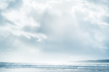 Beach and sea with cloudy sky and sunbeams.